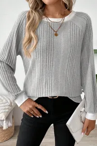 Detailed macro view of a grey ribbed knit long-sleeved sweater with round neck design