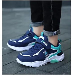Detailed close-up shot of navy blue waterproof boys' sports sneakers on stone pavement
