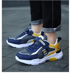Detailed view of stylish boys' blue and yellow sports sneakers on outdoor pavement.