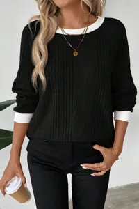 Close-up detail of the black ribbed sweater with contrast white collar and cuffs