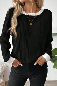 Close-up detail of black ribbed knit sweater featuring contrast white collar and cuffs