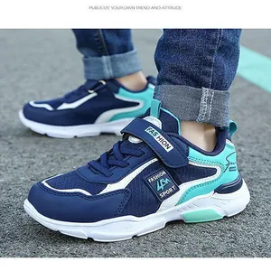 Close-up of boys' blue sports sneakers featuring hook-and-loop straps on asphalt.