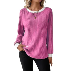 Close-up of pink ribbed knit sweater featuring white contrast cuffs and neckline