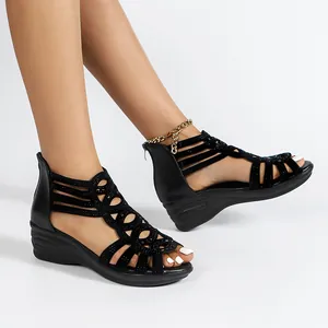 Side detail of women's black Roman wedge sandals with rhinestone cutouts and gold chain