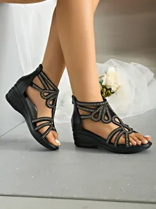 Elegante detailopname van zwarte sleehaksandalen met strasbandjes op een model.