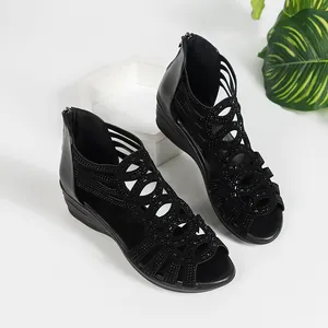 Close-up of black Roman wedge sandals featuring sparkling rhinestone and cut-out details.