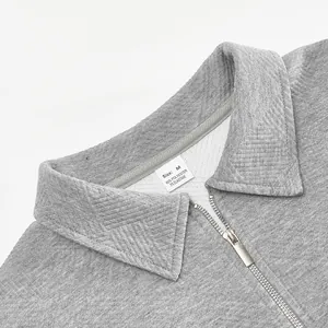 Primer plano del cuello de jacquard con textura y cremallera en la sudadera polo gris
