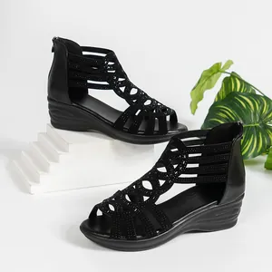 Detail view of black Roman wedge sandals featuring intricate cut-outs and rhinestones