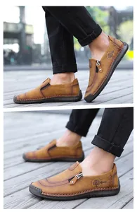 Detail view of men's casual brown leather loafers featuring a side zipper and embossed logo