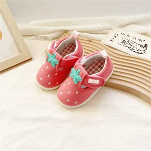 Détail de chaussures de bébé fraise rose avec une texture en tissu et velcro feuille.