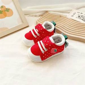 Vue détaillée de chaussures bébé rouges à motif fraise avec semelles souples blanches