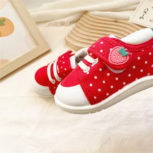 Gros plan détaillé de chaussures pour bébé rouges à pois avec scratch fraise mignon