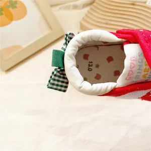 Détail d'une chaussure de marche pour bébé fille à pois rouges et nœud vert au talon