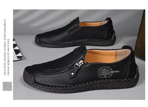 Detail view of men's black leather loafers with side zipper and decorative patch