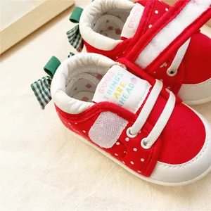 Détail de chaussures souples pour bébé à pois rouges avec étiquette brodée colorée