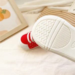 Gros plan sur la semelle souple antidérapante des chaussures bébé fraise rouge.