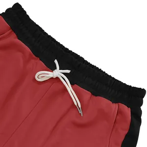Close-up detail of red heavy-duty sweatpants with black waistband and white drawstring ties