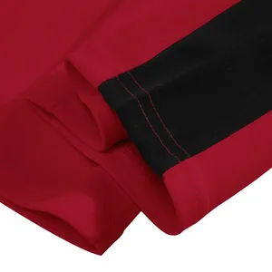 Close-up of red men's sweatpants featuring a black contrast side stripe and neat stitching.