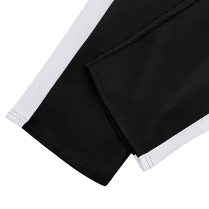 Close-up of black sweatpants leg cuffs with white side stripes and neat stitching