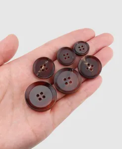 Detail of premium dark brown marbled buffalo horn buttons for cashmere coats held in hand