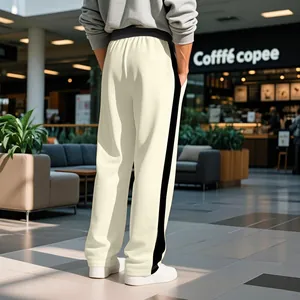 Rear view of men's cream sweatpants with black side stripes in a modern interior