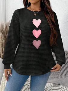 Detail of casual black sweatshirt with pink heart print and quilted square texture.