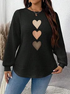 Detailed view of women's black waffle knit sweatshirt featuring a three-color heart print
