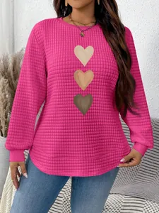 Detailed view of pink waffle knit sweatshirt with three heart graphics and curved hem