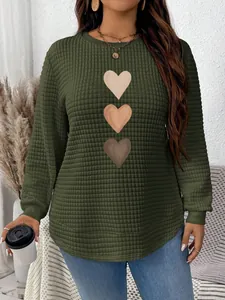 Close-up of olive green waffle knit sweatshirt featuring three heart graphics and rounded hem.