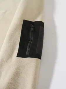 Close-up macro detail of black zipper sleeve pocket on beige coral fleece men sweatshirt