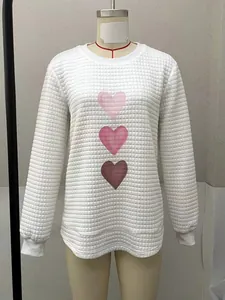 Detailed view of white waffle knit sweatshirt with three pink heart prints