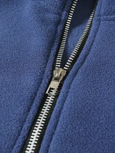 Nahaufnahme eines silbernen Metallreißverschlusses an einer blauen Fleecejacke für Herren