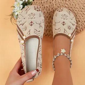 Close-up detail of knitted beige and brown slip-on flats with pearl accents