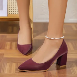 Detailed view of burgundy pointed-toe block heel pumps worn on foot with white beaded anklet