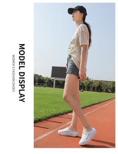 Modelo asiática con zapatos de balancín de malla blanca en una pista de atletismo.