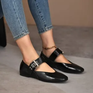 Close-up of black patent leather Mary Jane flats with stylish buckle strap details.