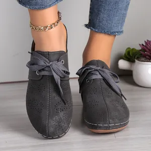 Close-up of dark grey hollowed-out lace-up mules for women in a stylish setting