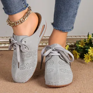 Close-up view of grey closed-toe hollow lace-up wedge mules with floral perforation detail