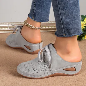 Detailed view of grey suede-like wedge mules featuring elegant hollow out lace-up design
