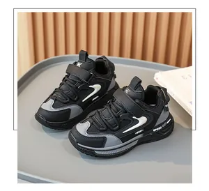 Close-up of black and grey children's sporty dad shoes on a grey tray background