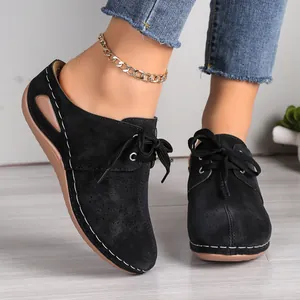 Close-up of black lace-up wedge sandals with hollow patterns and suede texture
