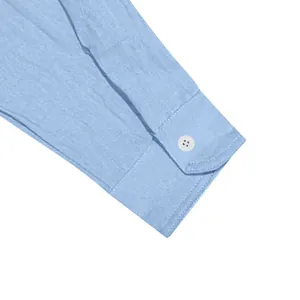 Gros plan détaillé d'un poignet de chemise bleu clair avec bouton blanc à quatre trous.