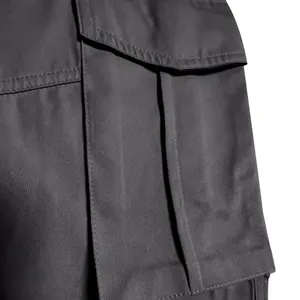Close-up detail of a large flap cargo pocket with pleats on charcoal grey trousers
