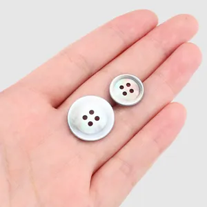 Botones de concha de labio negro japonés de alta gama para ropa mostrados en mano