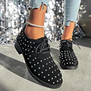Dettaglio scarpe stringate in camoscio nero con borchie argentate e comodo tacco largo.