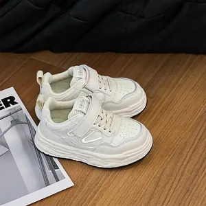 Dettaglio di scarpe casual bianche per bambini con velcro su pavimento in legno