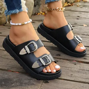 Detailansicht schwarzer Plateausandalen mit gravierten Schnallen und Riemen im Vintage-Stil.