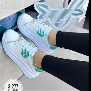 Detailed view of white platform sneakers with green accents and gold lace buckle