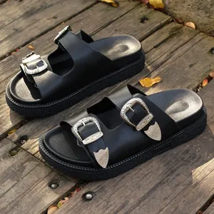 Schwarze Damen-Plateausandalen mit verzierten Silberschnallen auf rustikalem Holzdeck