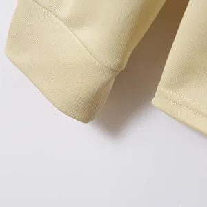Detail der atmungsaktiven Piqué-Struktur und des Bündchens an einem cremefarbenen Poloshirt.